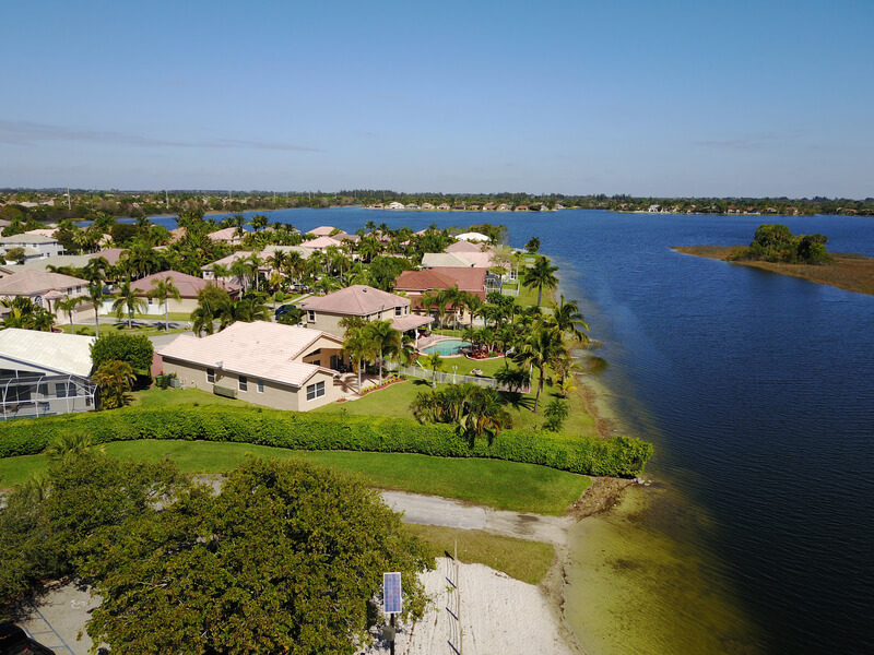 alt="Aerial view of traditional Florida waterfront homes situated along an expansive deep blue lake" 