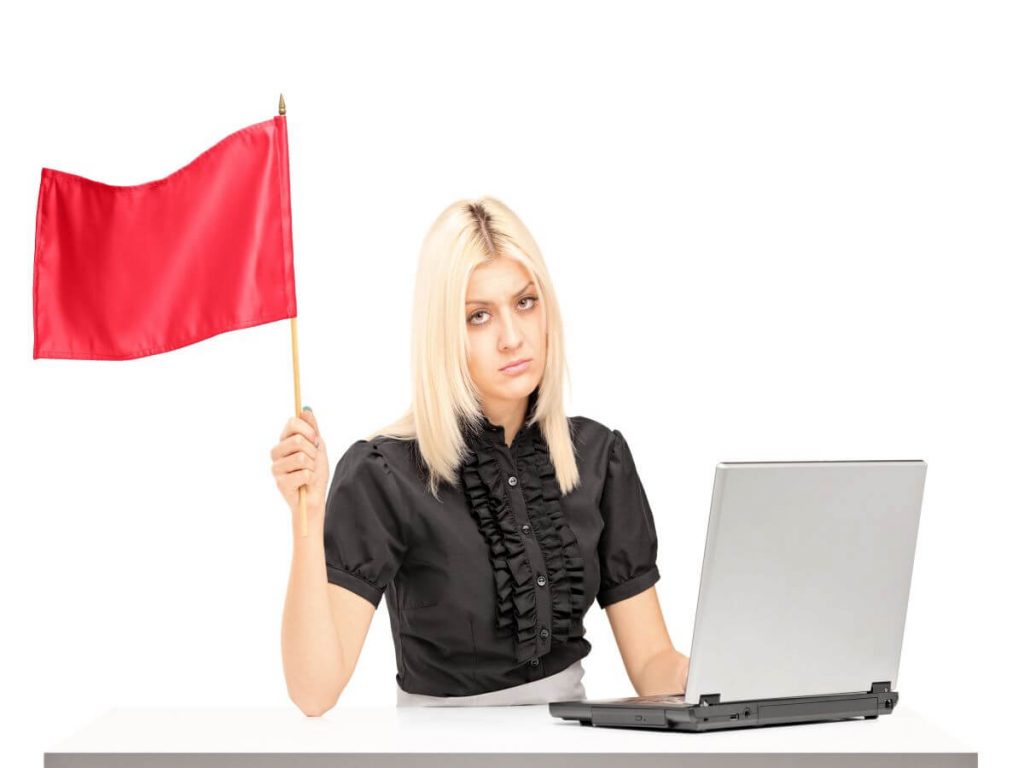 alt="Woman holding up a red flag to signify red flags in a listing agreement"