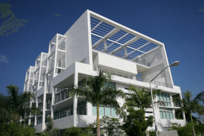 alt="Condos for sale in South Florida in a contemporary white building surrounded by palm trees."