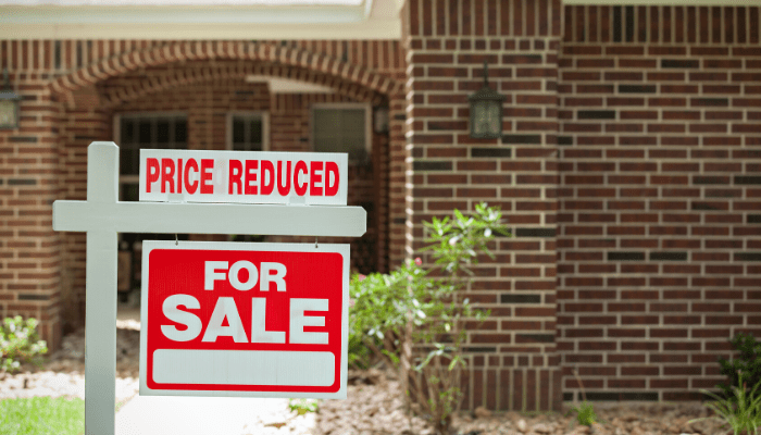 alt="Price reduced sign on a home for sale to demonstrate purchasing an affordable home."